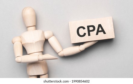 Wooden man shows with a hand to white board with text cpa,concept