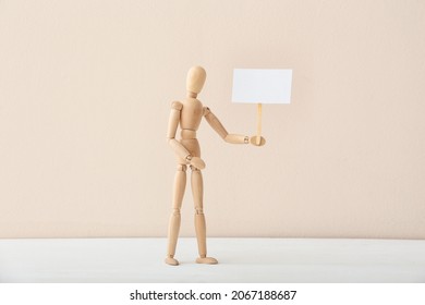 Wooden mannequin with blank placard on color background - Powered by Shutterstock