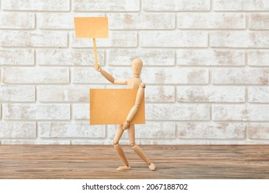 Wooden mannequin with blank placards near brick wall - Powered by Shutterstock