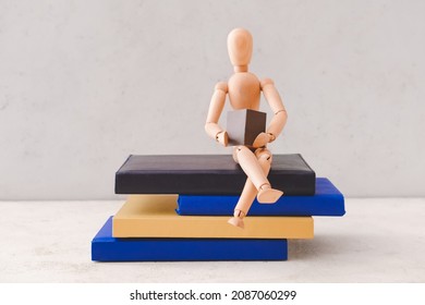 Wooden mannequin with books on light background - Powered by Shutterstock