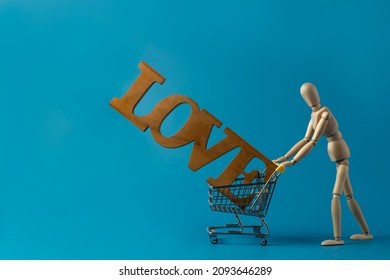 Wooden mannequin carrying shopping cart with wooden word ''love'' on blue background. - Powered by Shutterstock