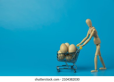 Wooden mannequin carrying shopping cart with chicken eggs on blue background. Concept for online shopping and fast delivery of fresh food. - Powered by Shutterstock