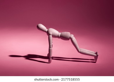 wooden mannequin doing push-ups from the floor on a pink background - Powered by Shutterstock