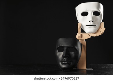 Wooden mannequin hand and plastic masks on black background, space for text. Theatrical performance - Powered by Shutterstock