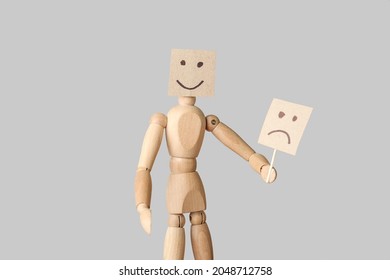 Wooden Mannequin Hiding Face Behind Emoticon On Light Background