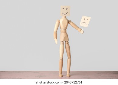 Wooden Mannequin Hiding Face Behind Emoticon On Light Background