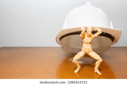 wooden mannequin holding a safety helmet - Powered by Shutterstock