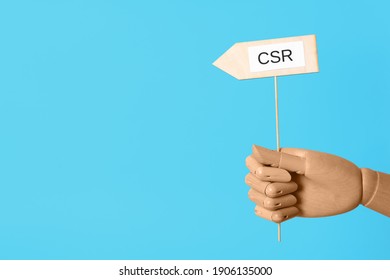 Wooden mannequin holding sign with abbreviation CSR on light blue background, closeup. Corporate social responsibility - Powered by Shutterstock