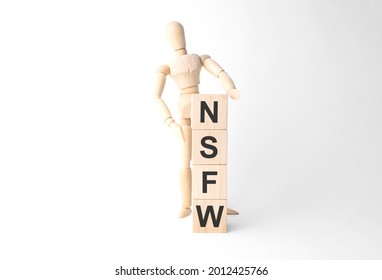Wooden mannequin near tower of cubes with word nsfw on table against light background