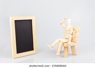 Wooden Mannequin With Photo Fram Sitting On Wood Chair On White Background.