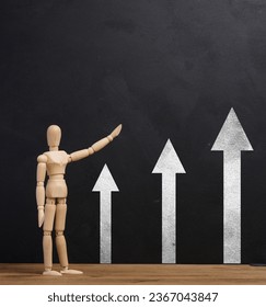Wooden mannequin points at black chalk board with arrows, growth indicators - Shutterstock ID 2367043847
