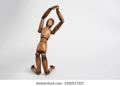 Wooden mannequin pose of praying man, kneeling and raising his hands up - Powered by Shutterstock