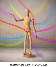 Wooden mannequin posed in front greyish background and colorful lines behind it
