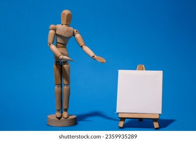 Wooden mannequin showing to blank white canvas isolated on blue background. Concept of representing messages with text for copy text or photo for representing artists. - Powered by Shutterstock