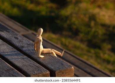 A wooden mannequin sits alone on a bench and looks into the distance. Concept of depression and loneliness. - Powered by Shutterstock