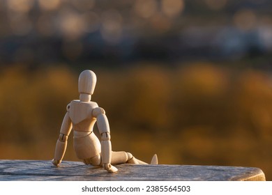 A wooden mannequin sits on a bench and looks at an autumn blurred landscape. The concept of loneliness, - Powered by Shutterstock