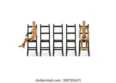 A wooden mannequin sits on a black chair on a white background. A minimal conception of a person who is exhausted, tired, depressed, desperate. Waiting. Puppet posture. - Powered by Shutterstock