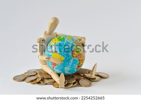 Wooden mannequin sitting with earth globe on pile of coins  - Concept of planet earth protection, globalization and economy