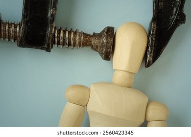 Wooden mannequin squeezed in iron vise tool - Concept of heachache, stress and psychological pressure - Powered by Shutterstock