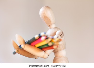 Wooden mannequin trying to represent human movements in moving actions. Anatomical model holds colorful pencils. - Powered by Shutterstock