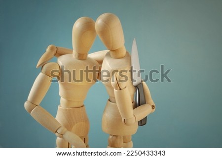 Wooden mannequins hugging each other with knife behind back - Concept of betrayal and disloyalty 