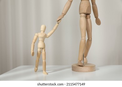 Wooden Mannequins Of Parent With Child On White Table Against Light Background. Family Day