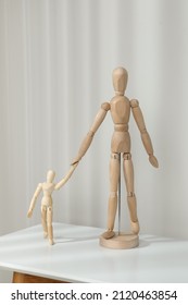 Wooden Mannequins Of Parent With Child On White Table Against Light Background. Family Day