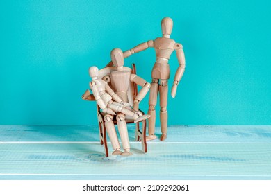 Wooden Mannequins Posing For A Family Portrait As Father And Mother Sitting In Armchair And Holding Her Baby