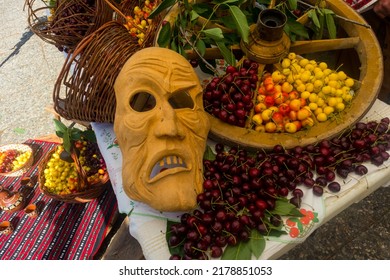 A wooden mask expressing emotions, and the cloth with cherries in the background