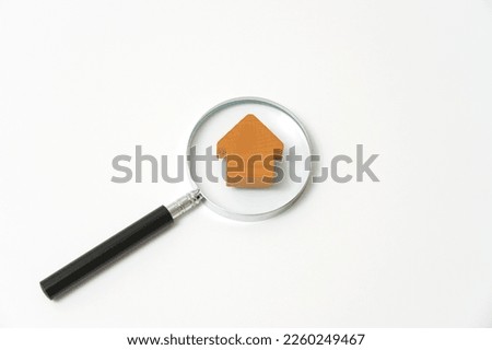 The wooden miniature house and a magnifying glass in white background