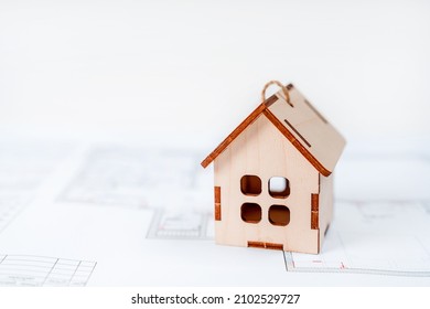 Wooden model of the house in the drawing of the apartment scheme. Design project of a new house - Shutterstock ID 2102529727