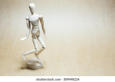 Wooden model jumping on light brown paper floor - Powered by Shutterstock