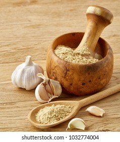 Wooden mortar and pestle with garlic and grind spices on rustic table, close-up, selective focus - Shutterstock ID 1032774004