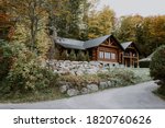 Wooden mountain house built from wood logs. Beautiful log house with porch, patio and driveway in peaceful forest scenery, Canada