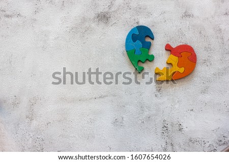 Wooden multicolor puzzle in the form of heart on gray background. Concept valentines day, relationship. Space for text