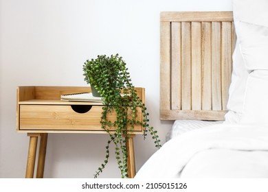 Wooden Nightstand With Houseplant And Notebook Near Light Wall In Bedroom