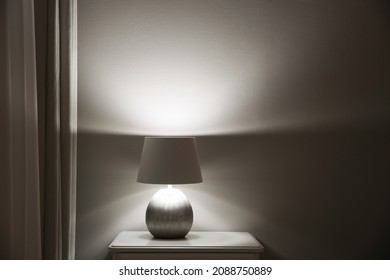 Wooden Nightstand With Modern Lamp Near Light Grey Wall, Space For Text. Interior Element