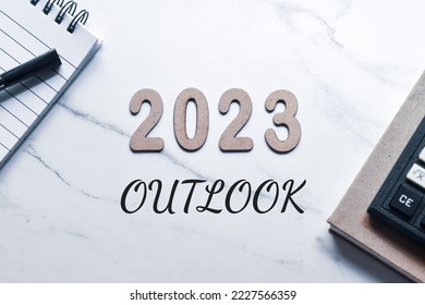 Wooden numbers 2023 with the text outlook on table. Top view, economic growth forecast concept.