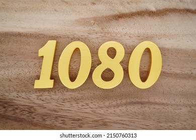 Wooden  numerals 1080 painted in gold on a dark brown and white patterned plank background.