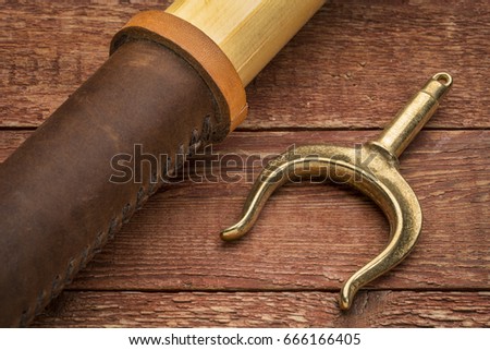 wooden oar and brass oarlock (rowlock) on rustic weathered wood background