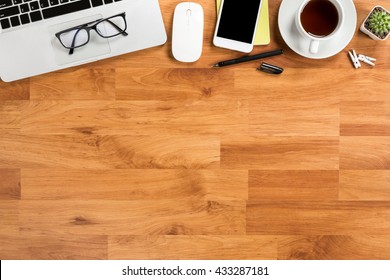 Wooden office desk table with laptop, coffee, smartphone and supplies. Top view with copy space.