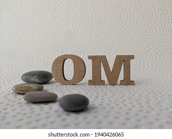 Wooden Ohm Mantra And Gray Stones On White Textured Background