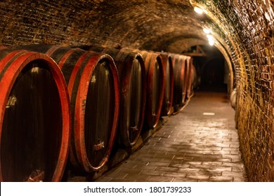 wooden old barrels in the rustic wine cellar with brick walls in villány hungary .