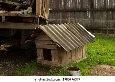 Wooden Old Doghouse In The Grass Near The House.one Old Empty Wooden Doghouse