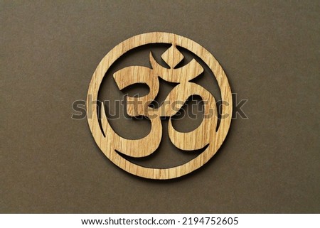 Wooden Om or Aum symbol of Hinduism and Buddhism on brown background
