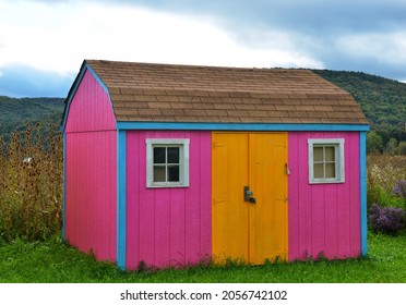 Wooden Outdoor Storage Shed With Two Windows, Located In Backyard Of Countryside. Unique Bold Color Design, Rarely Seen. American Traditional Style Shed.