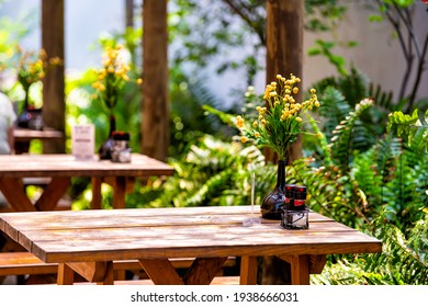 Wooden Outside Outdoor Sitting Restaurant Empty Area With Picnic Wooden Tables Chairs Bench In Patio Terrace Garden With Green Plants In Florida With Flower Bouquet And Condiments