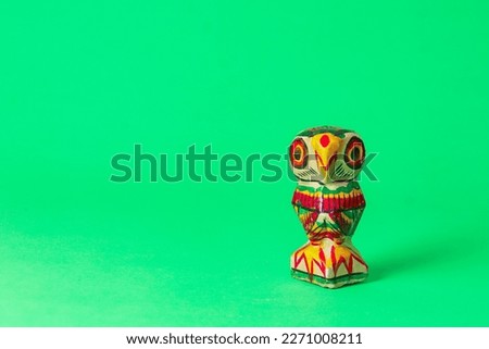 wooden owl hand-painted with vivid colors symbolising hindu goddess Lakshmi. these statues are locally made in West Bengal traditionally. shot taken against green background with copy space.