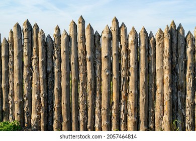 Wooden palisade made of logs. Log wooden fence. Sharp stakes in the ground. - Shutterstock ID 2057464814