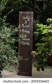 Wooden Panel In A Garden Restaurant With Three Rules. Relax, Sit Down And Drink